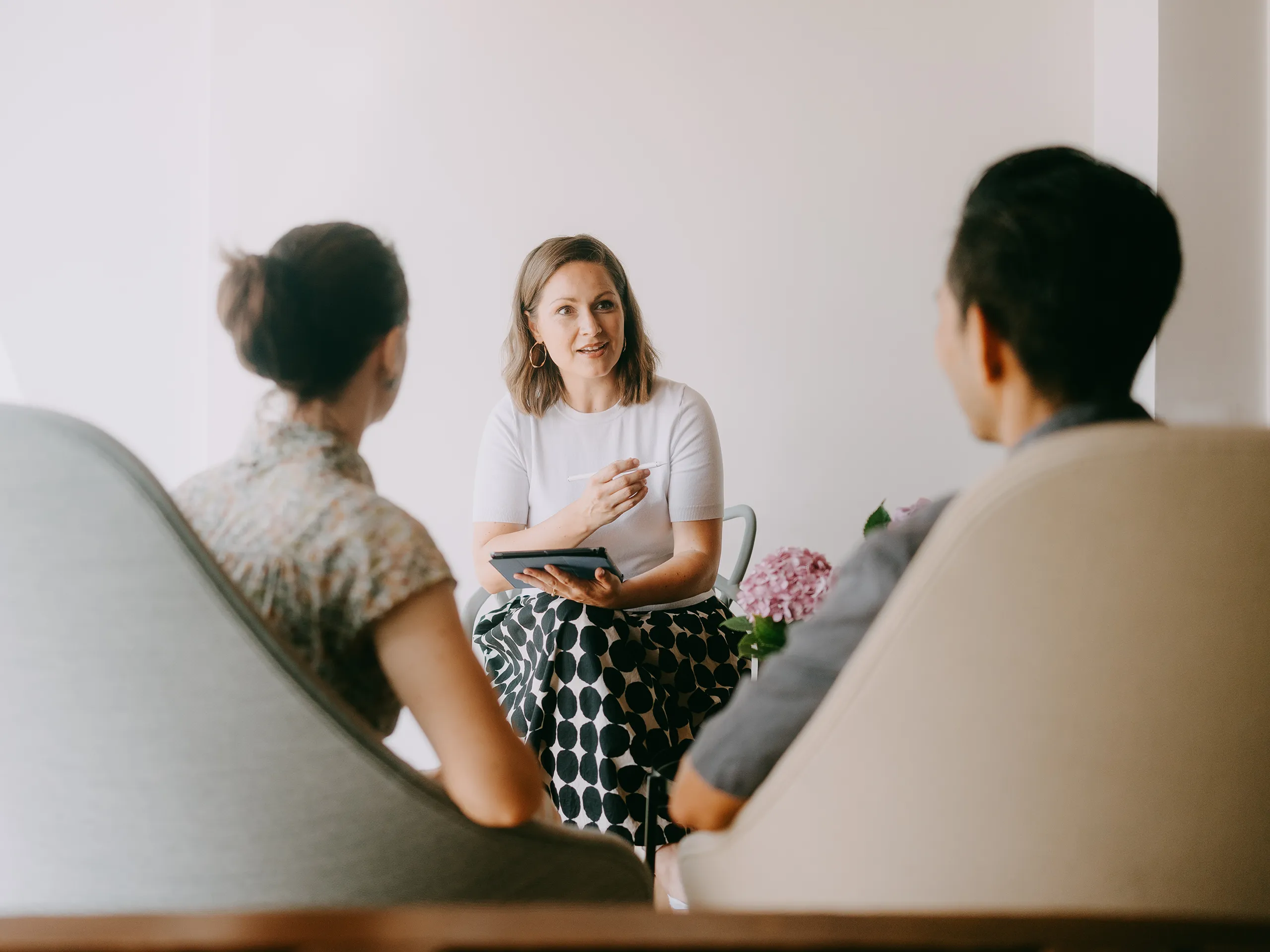 Woman having a conversation with two people in a bright room.