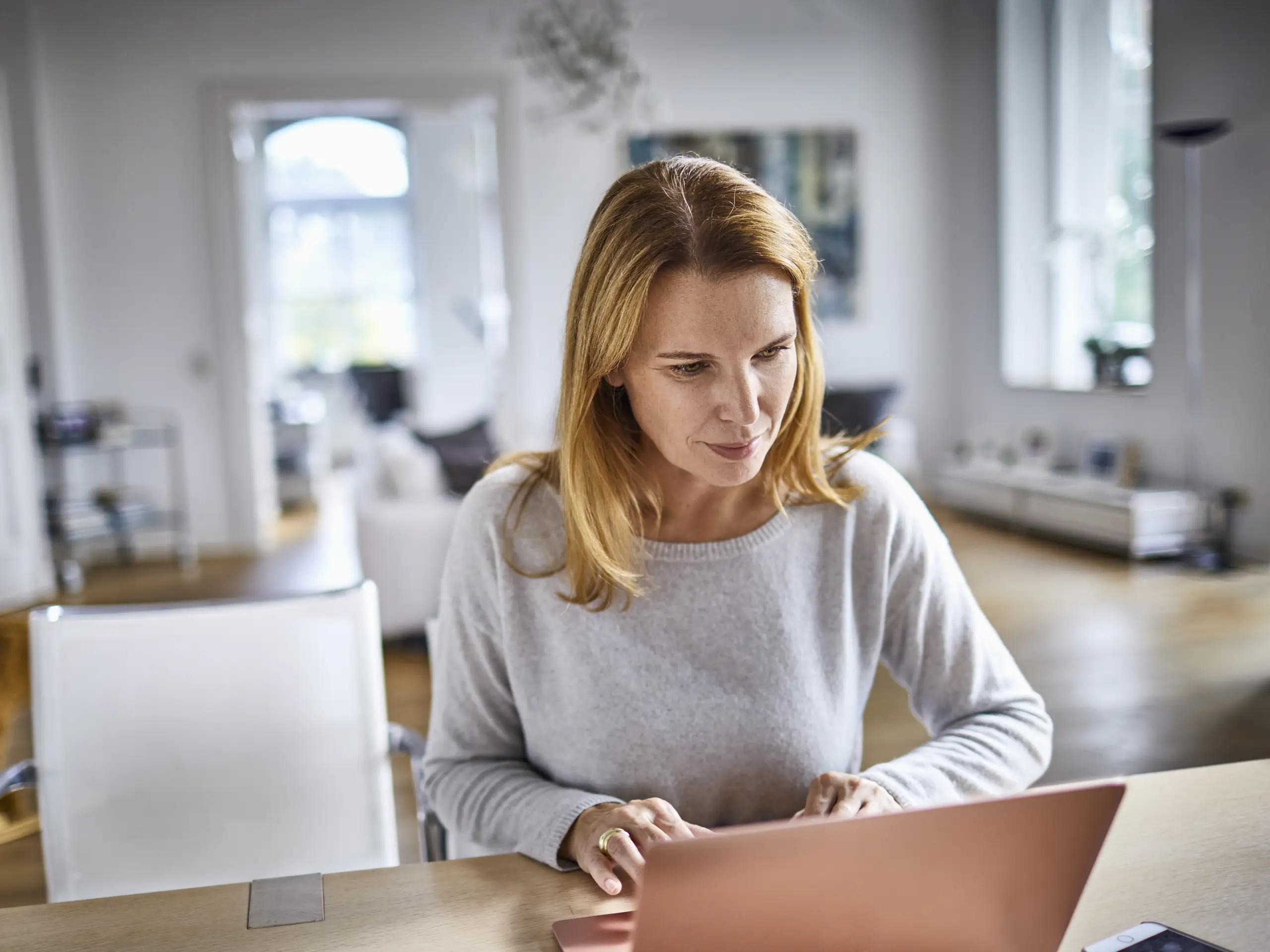 Person sitting at a table using a laptop in a living space.
