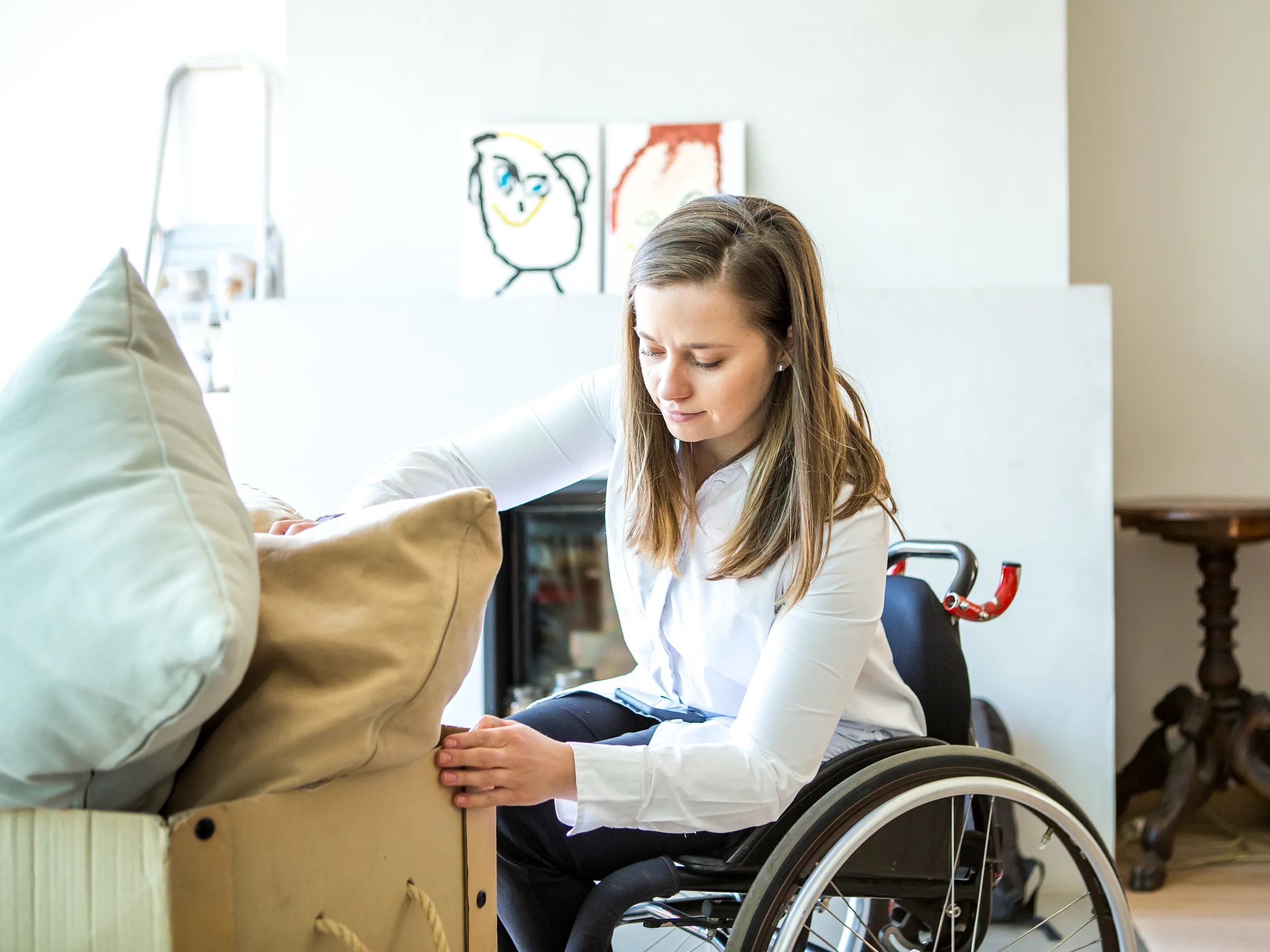 Person in a wheelchair adjusting a sofa cushion in an accessible living space