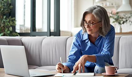 woman taking notes in front of a laptop